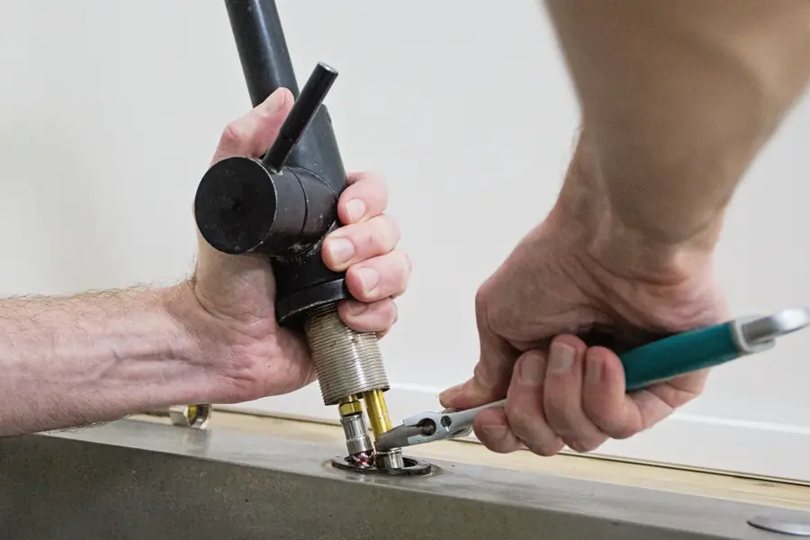 A professional plumber is installing and securing a new faucet in Rock Hill SC