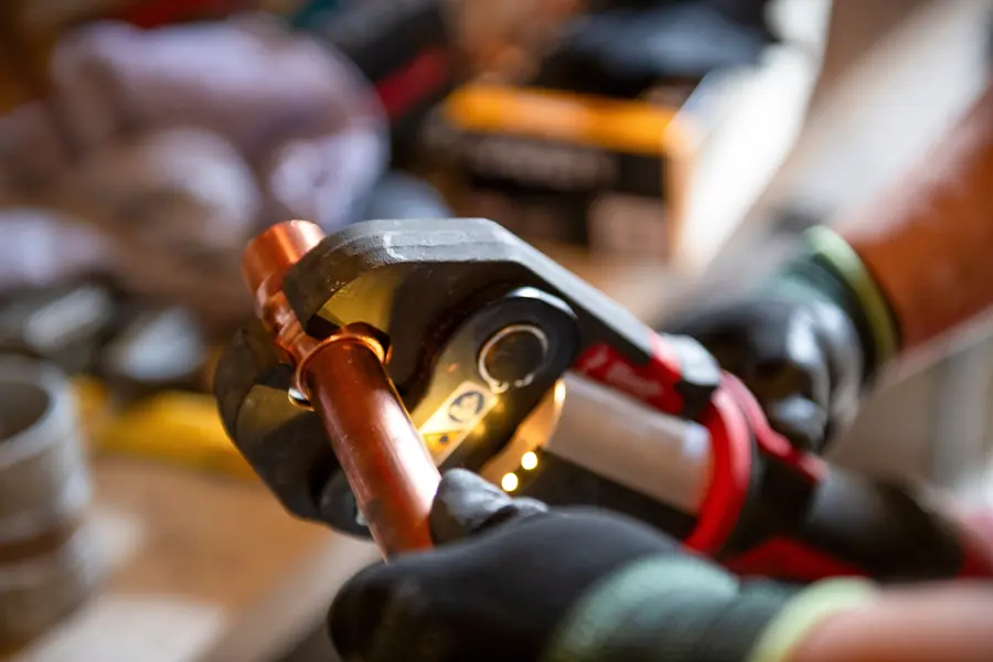 Cutting a copper pipe with a pipe cutter during plumbing service in Rock Hill SC.